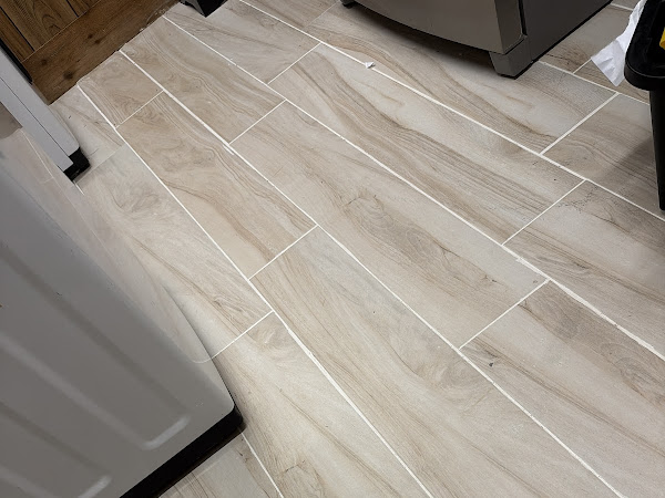 Light wood-look tile floor with staggered joints in a laundry room, pictured on Blueline’s Google listing